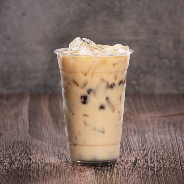 Iced coffee with boba pearls and ice in a clear plastic cup on a wooden table.