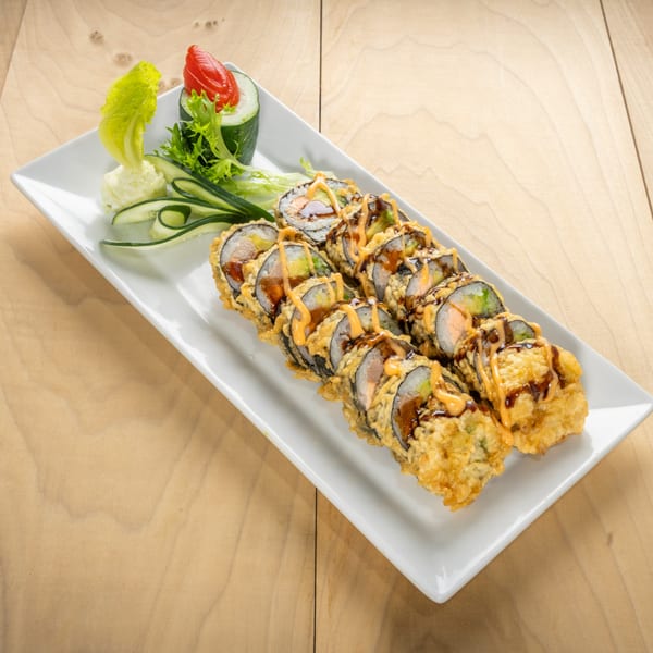 Crispy fried kosher sushi rolls drizzled with sauce, garnished with lettuce, cucumber, and tomato.