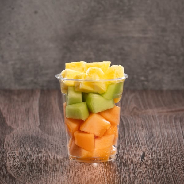 A clear plastic cup filled with layers of diced pineapple, honeydew, and cantaloupe.