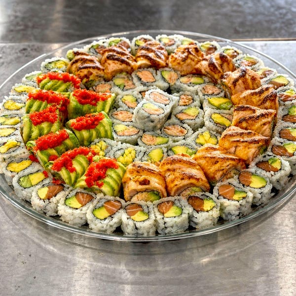 Large platter of kosher sushi rolls, including salmon, avocado, and grilled salmon varieties.